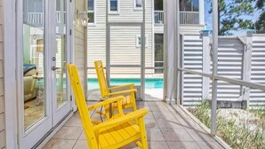 A covered patio with yellow chairs and a view of a house and swimming pool. - Kiva's Jewel - Guest House (Gulf Shores)