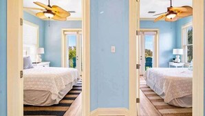 A hallway leading to two bedrooms, each with a bed, a ceiling fan, and a nightstand. - Kiva's Jewel - Guest House (Gulf Shores)