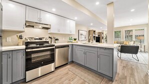 A modern kitchen with grey cabinets, stainless steel appliances, and a large island. - Pet-Friendly 1BR With Office & Fenced Yard (Ottawa)