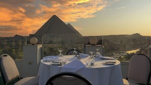 Een tafel voor twee met uitzicht op de piramides bij zonsondergang.