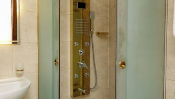 A bathroom with a glass-enclosed shower, a white sink, and a mirror.