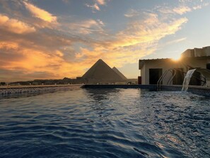 Piscina con vista a las pirámides al atardecer.