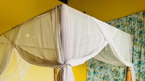 A bed with a canopy, a floral curtain, and a yellow wall.