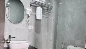 A modern bathroom with a white sink, round mirror, and toilet. - Hotel Jay Jay (Aizawl)