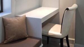 A modern room with a white desk, a cushioned bench, and a chair. Shelves with decorative items are mounted on the wall. - Hotel Jay Jay (Aizawl)