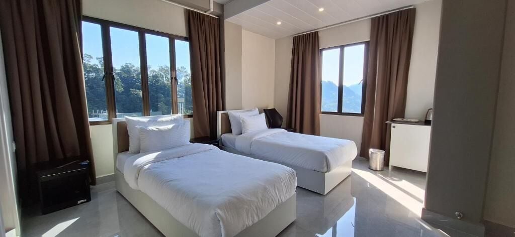 A hotel room with two beds, a desk, and a view of the outdoors.