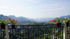 A balcony with potted plants and a view of a mountainous landscape. - Hotel Jay Jay (Aizawl)