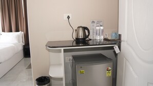 A compact hotel room with a kitchenette, including a kettle, coffee maker, and water bottles. - Hotel Jay Jay (Aizawl)