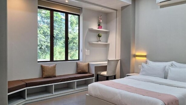 A modern bedroom with a bed, bedside tables, a bench, and a desk. - Hotel Jay Jay (Aizawl)