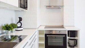 Une cuisine moderne avec des meubles blancs, un évier en acier inoxydable, une machine à café Bosch et un four encastré.
