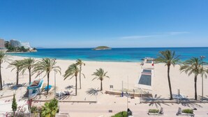 Une vue sur la plage, avec des palmiers, une plage de sable et un ciel bleu dégagé.