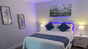 Une chambre à coucher moderne, avec un lit, des tables de chevet et des œuvres d’art murales.