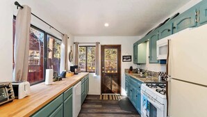 A compact kitchen with teal cabinets, a wooden countertop, a stove, and a refrigerator. - Slopeside Cabin C W Hot Tub & Slope View Parking (Big Bear Lake)