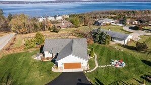 A residential area with a house featuring a garage, a lawn, and a view of a lake. - Design-forward Lake Views Bay Harbor (Petoskey)