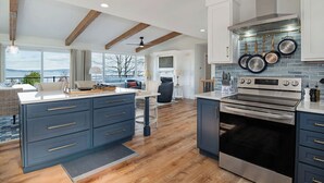 A modern kitchen with a large island, stainless steel appliances, and a view of the outdoors. - Design-forward Lake Views Bay Harbor (Petoskey)