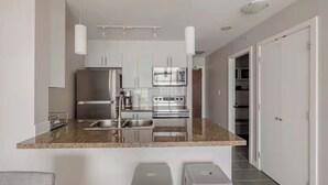 Una cocina moderna con electrodomésticos de acero inoxidable, encimera de granito e iluminación colgante.