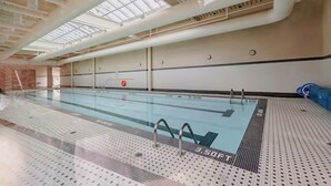 Una piscina interior con carriles delimitados, una silla de salvavidas y un techo con tragaluces.