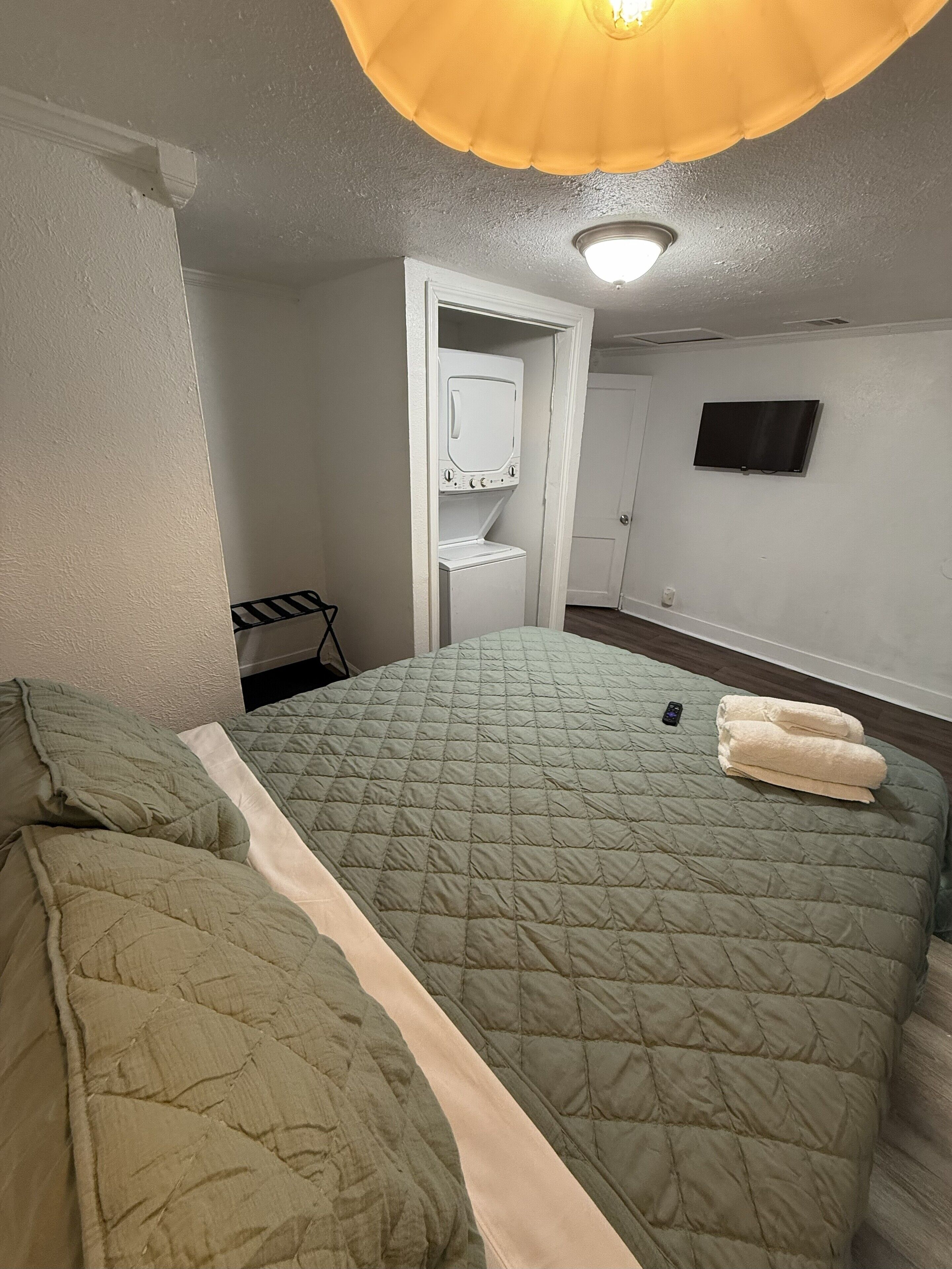 Une chambre avec un lit, un lave-linge, une télévision et une porte.