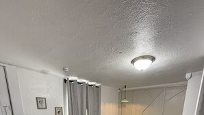 A bedroom with a bed, wooden flooring, a ceiling light, and a door. - 1BR Minutes to Stockyards • Fast Wi-Fi + Parking (Fort Worth)