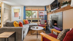 A cozy living room with a fireplace, a sofa set, a coffee table, and a television. - The Keep | Ski-In/Out Toby Chair | Ground Floor (Panorama)