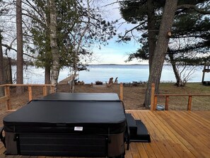 Eine Terrasse mit Whirlpool, Holzgeländern und Blick auf einen See.