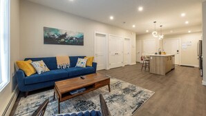 Un appartement moderne avec un canapé bleu, une table basse en bois et un îlot de cuisine.