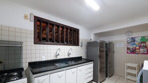 A kitchen with white cabinets, a black countertop, a stainless steel refrigerator, and a stove. - House w/ Pool 200 m From the Beach Pro0003 (Camaçari)