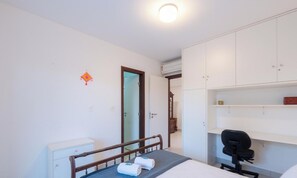 Une chambre d’hôtel équipée d’un lit, d’un bureau, d’une chaise, d’une armoire et d’un appareil de climatisation.