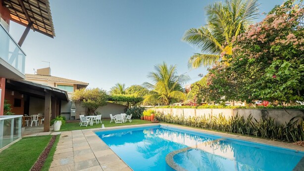 A swimming pool surrounded by a garden with palm trees and flowering plants. - House w/ Pool 200 m From the Beach Pro0003 (Camaçari)