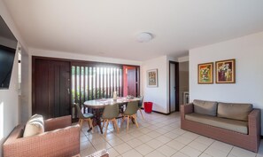 Un coin repas avec une table ronde et des chaises, un canapé et une poubelle rouge.