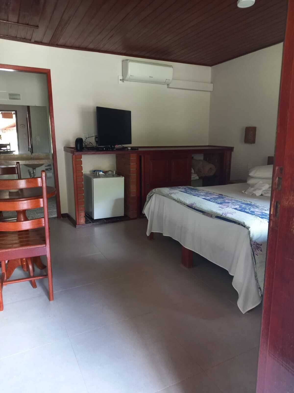 A bedroom with a bed, a desk, a television, and a small refrigerator.