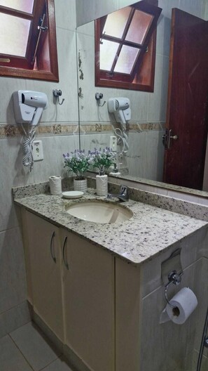 A bathroom with a sink, two hair dryers mounted on the wall, a mirror, and a toilet paper holder. - Pousada Caminho das Candeias (Nova Friburgo)
