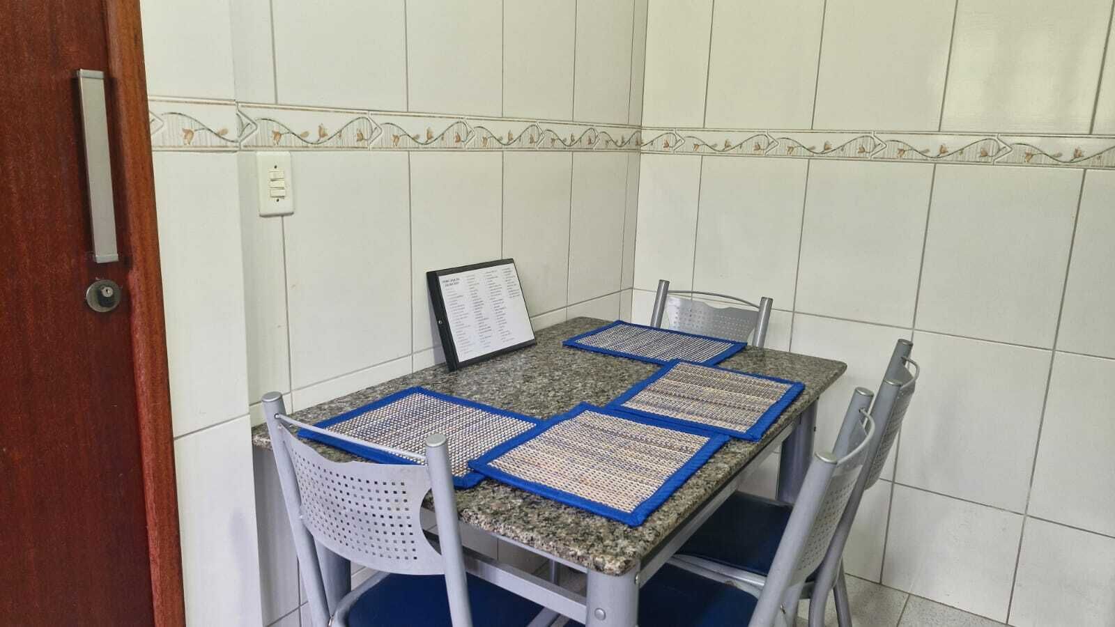 A dining area with a table and four chairs, a menu stand, and a tiled wall.