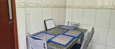 A dining area with a table and four chairs, a menu stand, and a tiled wall.