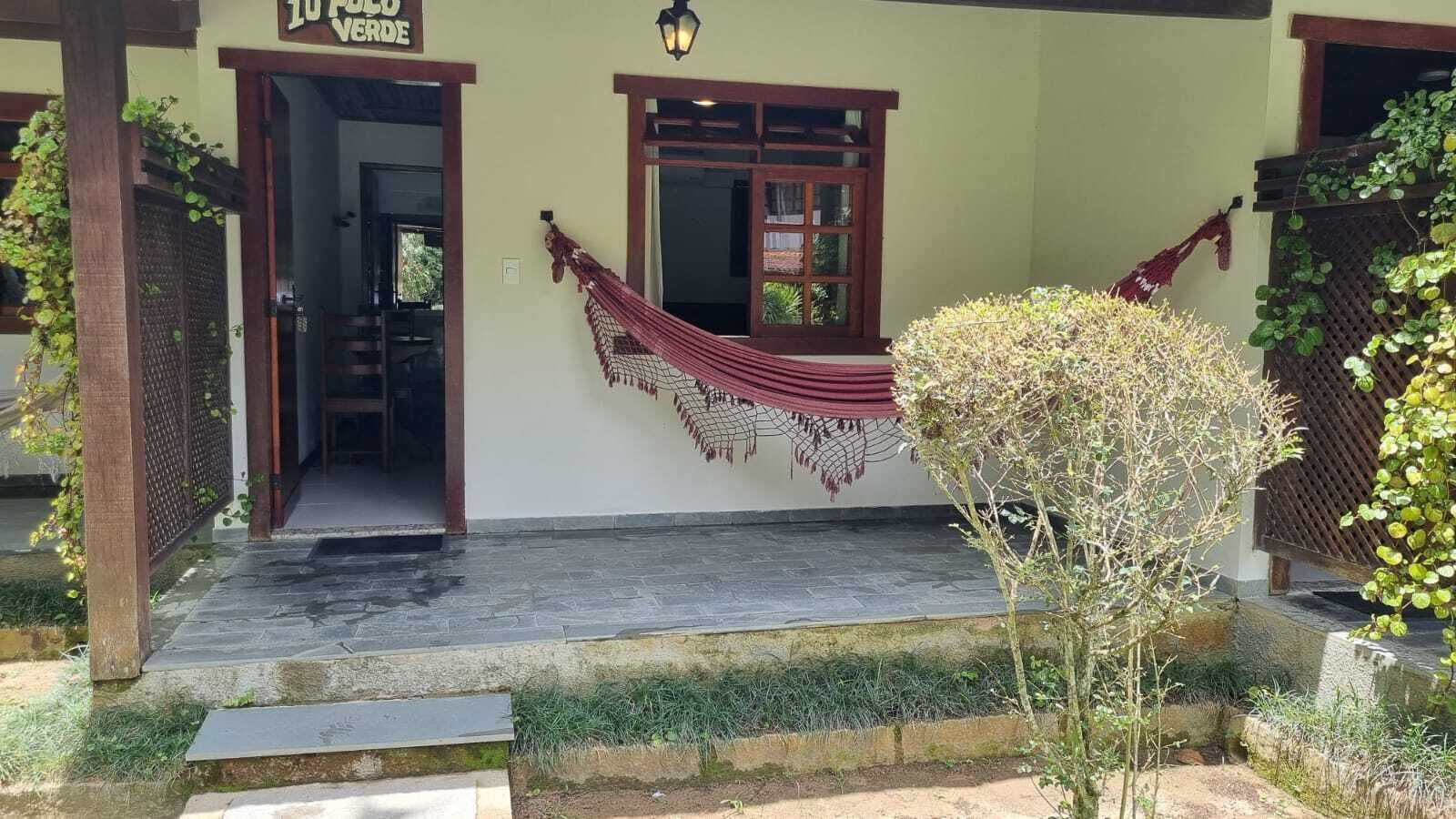 A building entrance with a wooden door, a hammock, and a sign that reads "LO PALO VERDE".