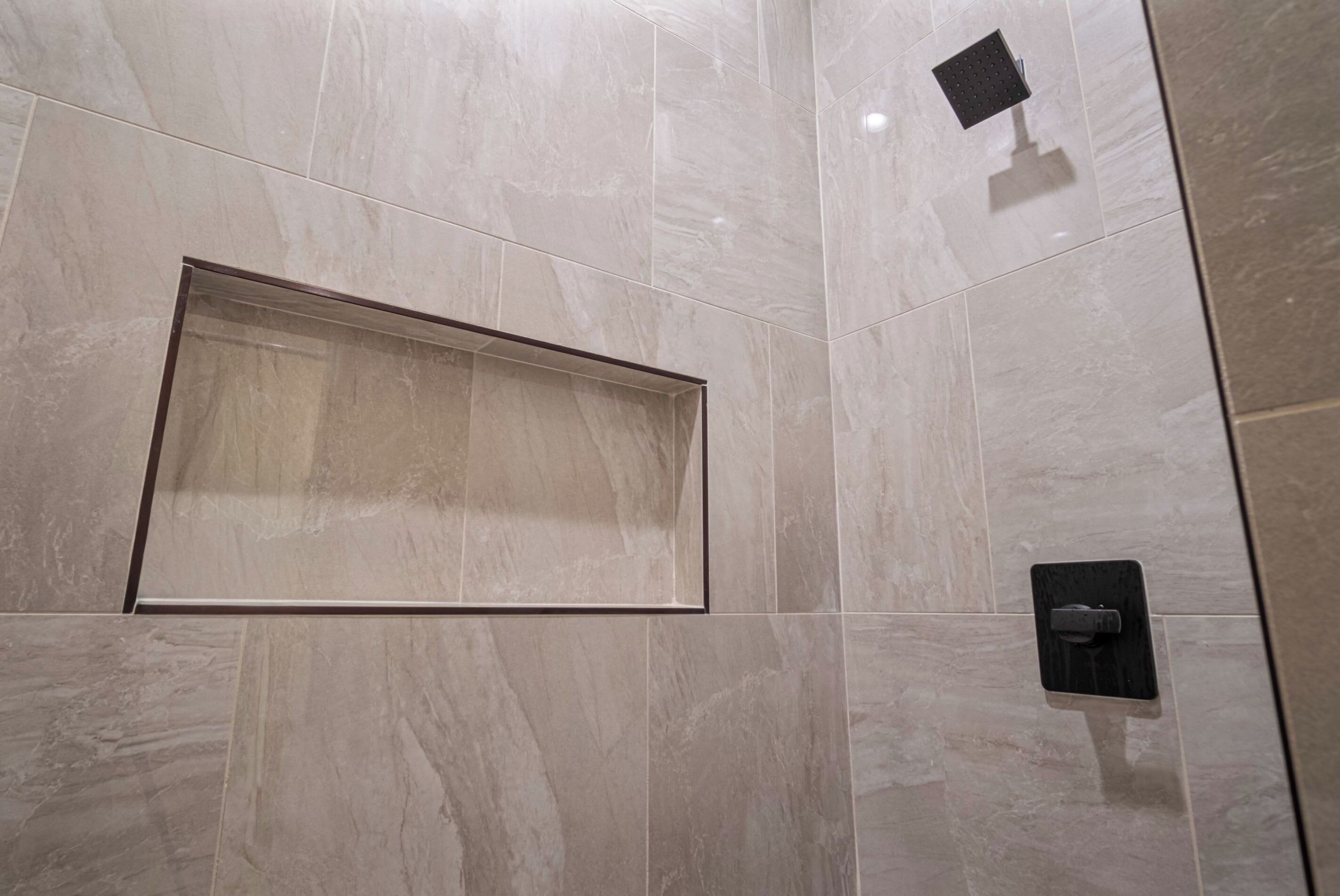 Un baño moderno con un espejo grande, un cabezal de ducha y un panel de control.