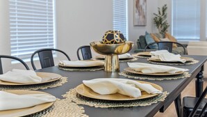 Une table à manger dressée avec des assiettes, des serviettes et un saladier décoratif.