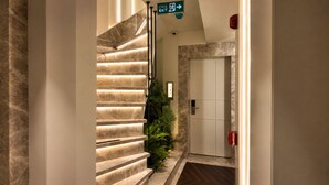 A marble staircase leading to a door with a green exit sign above. - alaturka mansion (İstanbul)