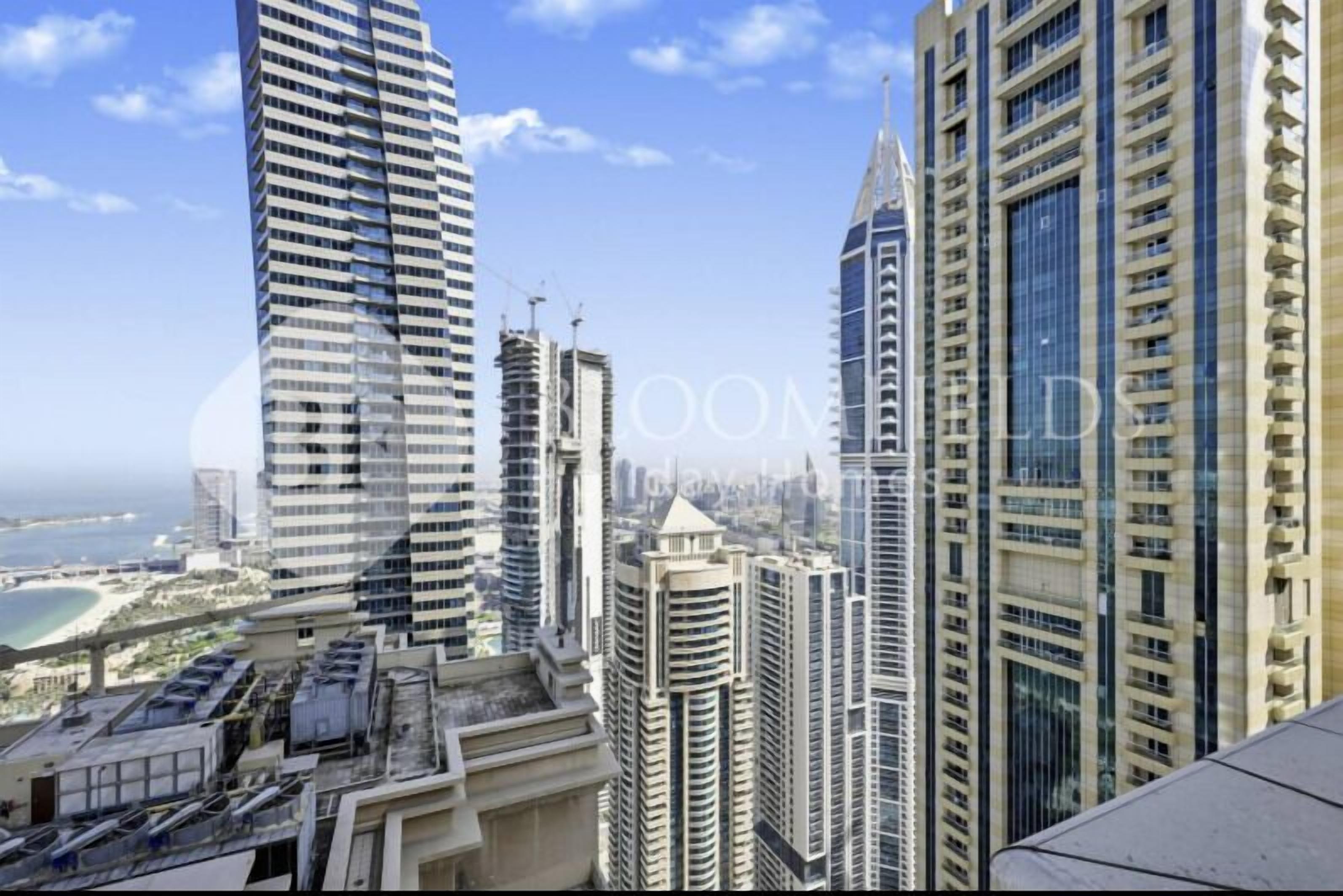 A high-rise building with a modern architectural design, featuring multiple balconies and a prominent glass facade.