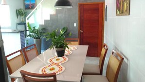 Zona pranzo con tavolo imbandito per quattro persone, circondato da sedie e un vaso con una pianta sul tavolo.
