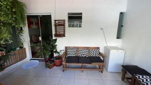 Una zona patio accogliente con un divano di legno, un tavolino e piante in vaso.