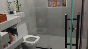 Un bagno moderno con doccia vetrata, un water e un angolo lavabo con articoli da toilette.