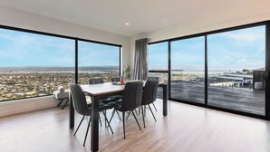Un comedor moderno con una gran mesa y sillas, ventanas amplias que ofrecen vistas a la ciudad y suelo de madera.