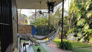 Une terrasse avec un hamac, un banc et une table recouverte d’une nappe verte.