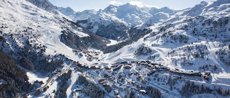 A snow-covered mountain village with winding roads and buildings nestled among trees.