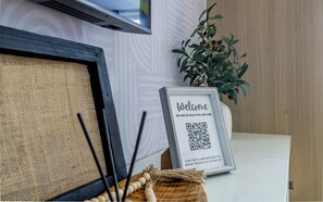 A framed welcome sign with a QR code, a potted plant, and a rustic woven mat. - The Viridian (Nairobi)