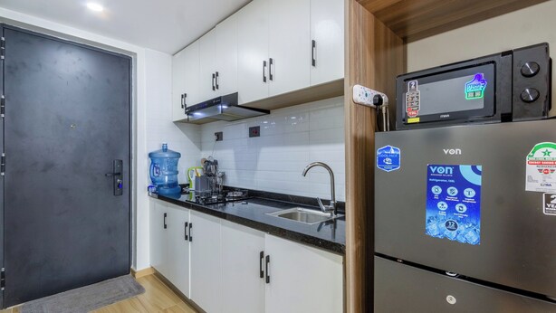 Una cocina moderna con armarios blancos, un refrigerador de acero inoxidable y un microondas integrado.