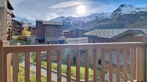 Un pueblo de montaña con edificios tradicionales, un balcón de madera y una vista despejada de montañas nevadas.