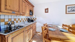 Una cocina con armarios de madera, salpicadero de azulejos y una mesa de comedor preparada para cuatro.