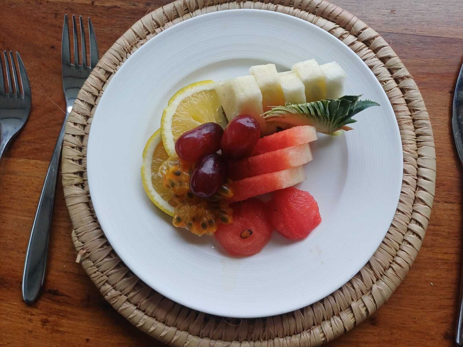 A plate of assorted fruits on a woven placemat.